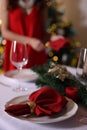 Woman setting table for Christmas dinner at home, focus on plate, napkin and decor Royalty Free Stock Photo