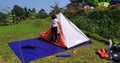 A woman is setting up a white, orange, blue cloth tent