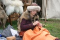 A woman sewing wearing furs at The Battle of Hastings reenactment in the UK