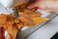 woman sewing dried tree leaves by machine