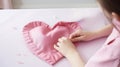 Woman sewing pink heart Pillow out of fabric Red satin bow on white background