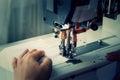 A woman sews on an industrial flat-seam sewing machine. Soft focus