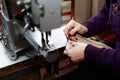 A woman sews a leather strip with a special sewing machine for leather, used in the production of handbags / shoes Royalty Free Stock Photo