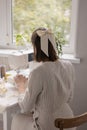 woman sews in a workshop or at home on a sewing machine. A young European woman in light clothes works