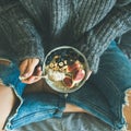 Woman in shabby jeans and sweater eating breakfast, square crop