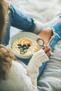 Woman in shabby jeans and sweater eating vegan breakfast Royalty Free Stock Photo