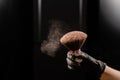 A woman shakes a large powder brush with clouds of dust on a black background. Treatment after instant tanning Royalty Free Stock Photo