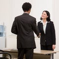 Woman shaking hands with co-worker at desk