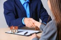 Woman shaking hands with real estate agent at table in office. Home insurance Royalty Free Stock Photo