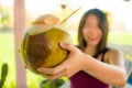 Woman in shallow depth of focus holding young coconut happy and cheerful smiling outdoors enjoying the coconut water drink during Royalty Free Stock Photo