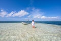 Woman in shallow sea with boat