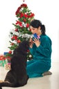 Woman sharing Christmas gift with her dog