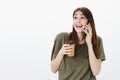 Woman sharing with friend during mobile talk with positive news. Studio shot of overwhelmed happy young girl, holding Royalty Free Stock Photo