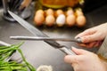 Woman sharpening kitchen knife with grindstone in the kitchen, kitchen knife. Close up view on hands