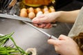 Woman sharpening kitchen knife with grindstone in the kitchen, kitchen knife. Close up view on hands