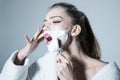 Woman shaves her face with sharp blade of straight razor. Woman with face covered with foam holds straight razor in hand Royalty Free Stock Photo