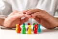 Woman sheltering colorful pawns at table, closeup. Social inclusion concept