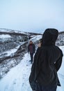 Woman shelters from the extreme cold, taking a photo of her husband in a totally snowy and mountainous environment in Iceland with Royalty Free Stock Photo