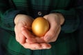 Woman in shirt holds golden egg