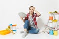 Woman in shock holds bundle of dollars, cash money, sits on floor with instruments for renovation apartment isolated on Royalty Free Stock Photo