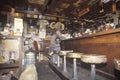 Woman shopkeeper sitting on bar stool in junk store, Los Angeles, California