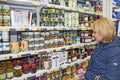 Woman shopper choosing canned olives in store. Canned food in grocery shop