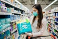 Woman shopper with mask and gloves panic buying disposable diapers.Preparing for pathogen virus pandemic quarantine.Prepper buying