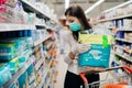 Woman shopper with mask and gloves panic buying disposable diapers.Preparing for pathogen virus pandemic quarantine.Prepper buying