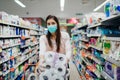 Woman shopper with mask and gloves panic buying and hoarding toilette paper in supply store.Preparing for pathogen virus pandemic