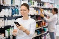 Woman shopper scanning a barcode on a cosmetics package with her phone. Searching for information via Internet