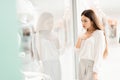 Woman in shopping mall. Girl is standing near store window looking at new dress. Royalty Free Stock Photo