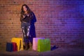 Woman with Shopping Bags Using Cell Phone Against Brick Wall Royalty Free Stock Photo