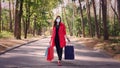 Woman with shopping bags. woman, in protective mask, with colored shopping bags in her hands, walking through city park Royalty Free Stock Photo