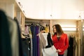 Woman shopping choosing dresses looking in mirror uncertain Royalty Free Stock Photo