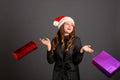 Woman shopping for christmas gifts. Young caucasian girl looking up smiling with shopping bags and santa hat. Copy space on the Royalty Free Stock Photo