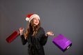 Woman shopping for christmas gifts. Young caucasian girl looking up smiling with shopping bags and santa hat. Copy space on the Royalty Free Stock Photo