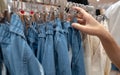 Woman shopping denim pants in clothing store. Woman choosing clothes. Jeans on hanger hanging on rack in clothing store. Fashion Royalty Free Stock Photo