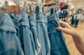 Woman shopping denim pants in clothing store. Woman choosing clothes. Jeans on hanger hanging on rack in clothing store. Fashion Royalty Free Stock Photo