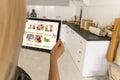 Woman shopping food online using a digital tablet at the kitchen, close-up view on a tablet screen. Concept of buying Royalty Free Stock Photo