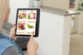 Woman shopping food online using a digital tablet at the kitchen, close-up view on a tablet screen. Concept of buying Royalty Free Stock Photo