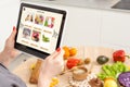 Woman shopping food online using a digital tablet at the kitchen, close-up view on a tablet screen. Concept of buying Royalty Free Stock Photo