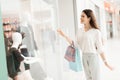 Woman in shopping mall. Girl is standing near store window looking at new dress. Royalty Free Stock Photo