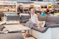 Woman shopping for new sofa in furniture store.