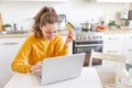 Woman shopping online and paying with gold credit card. Young girl sitting with laptop buying on Internet enter credit Royalty Free Stock Photo