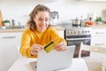 Woman shopping online and paying with gold credit card. Young girl sitting with laptop buying on Internet enter credit card Royalty Free Stock Photo