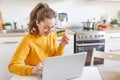 Woman shopping online and paying with gold credit card. Young girl sitting with laptop buying on Internet enter credit card Royalty Free Stock Photo