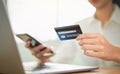 Woman shopping online on smartphone and holding back view of the credit card and enter the payment code for the product.