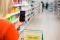 Woman shopping in supermarket and using mobile device Royalty Free Stock Photo