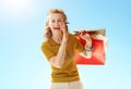 Woman with shopping telling exciting news against blue sky