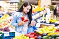 Woman shopping for vegetables holds red peppers and her purse in hands in the farmers market Royalty Free Stock Photo